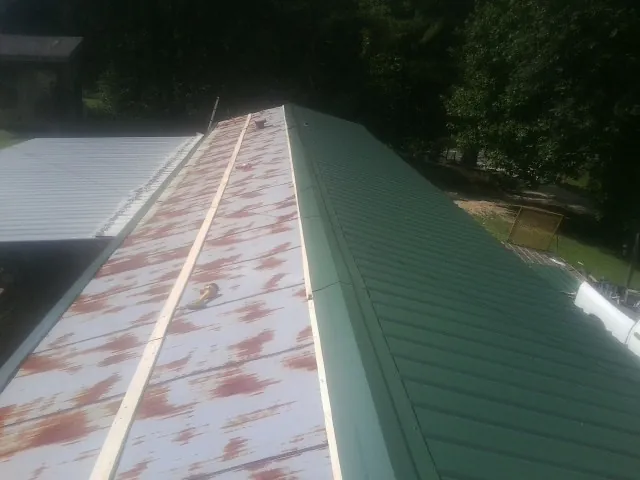 Old rusted panels beside newly installed green metal roofing — Wind Damage Roof Repair by Roofing Brothers in Cardinal