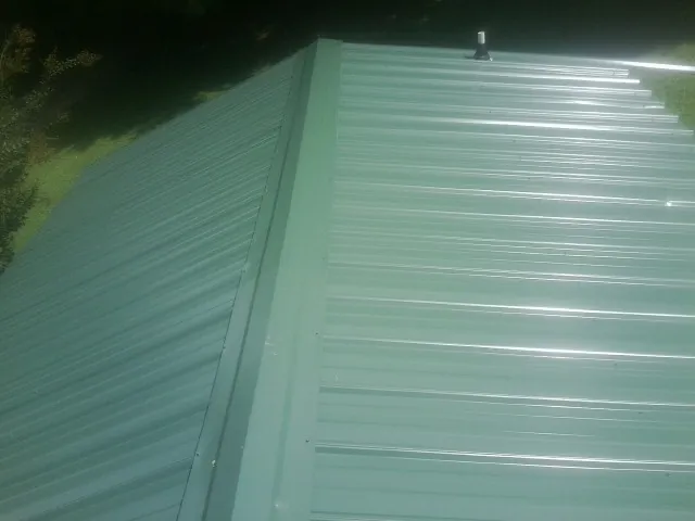 New green metal panels meeting at the ridge of a roof — Flat Roof Repair work by our crew in Cardinal