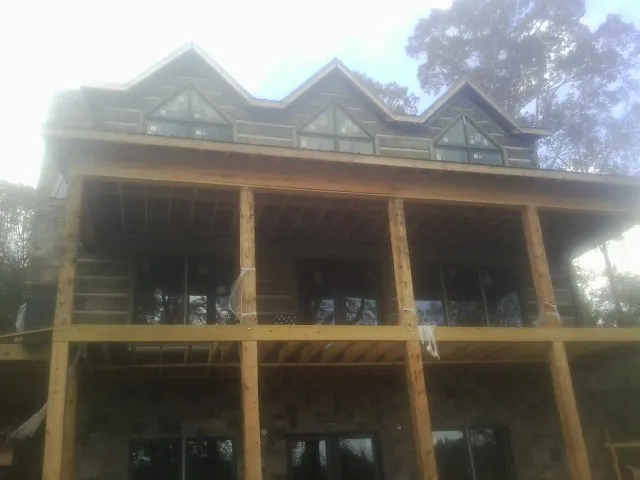 Dormers and porch framing on a large log home under construction — Roof Coating work by our crew in Cardinal