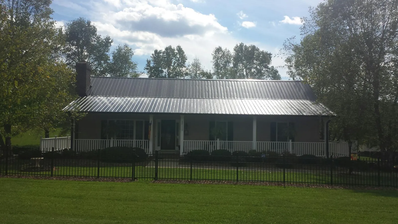 Gray metal roof on a brick ranch with a full width front porch — Gutter Guard Installation work by our crew in Cardinal